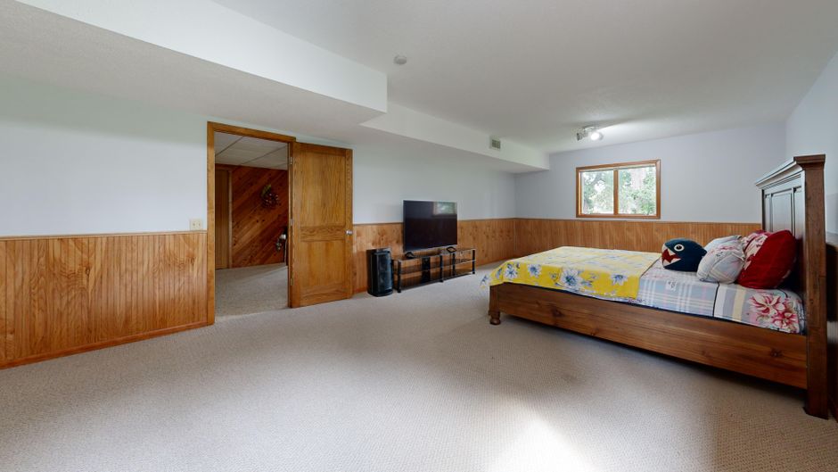 Finished basement room with a bed near an egress window