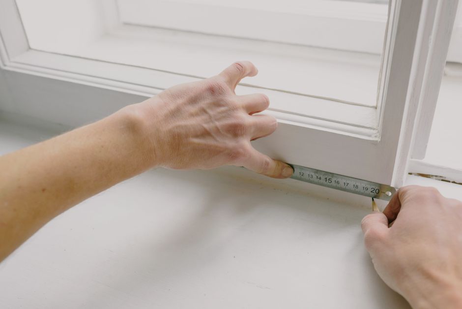 Measuring tape against a basement egress window opening