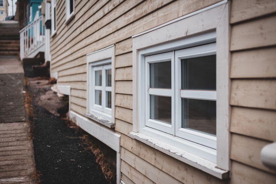 Two basement windows of different sizes on an exterior foundation wall