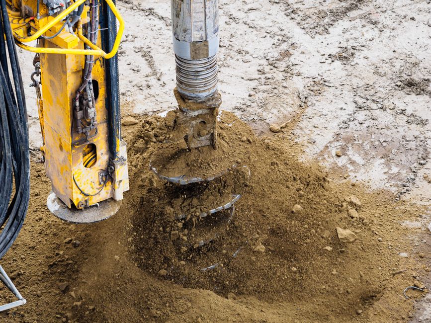 Excavated soil beside a foundation wall where an old window well has been removed