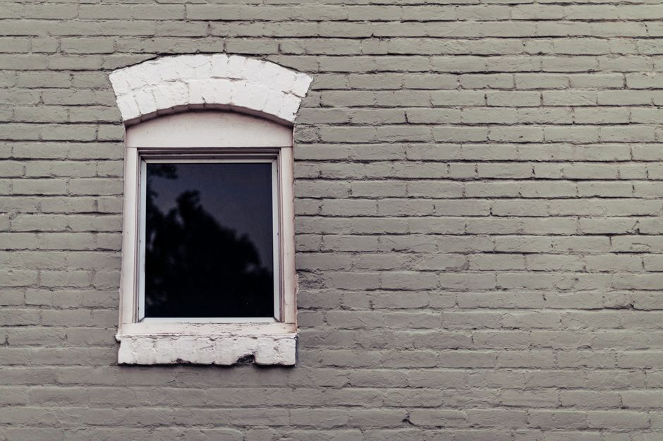 A corrugated metal window well installed against a poured concrete foundation wall