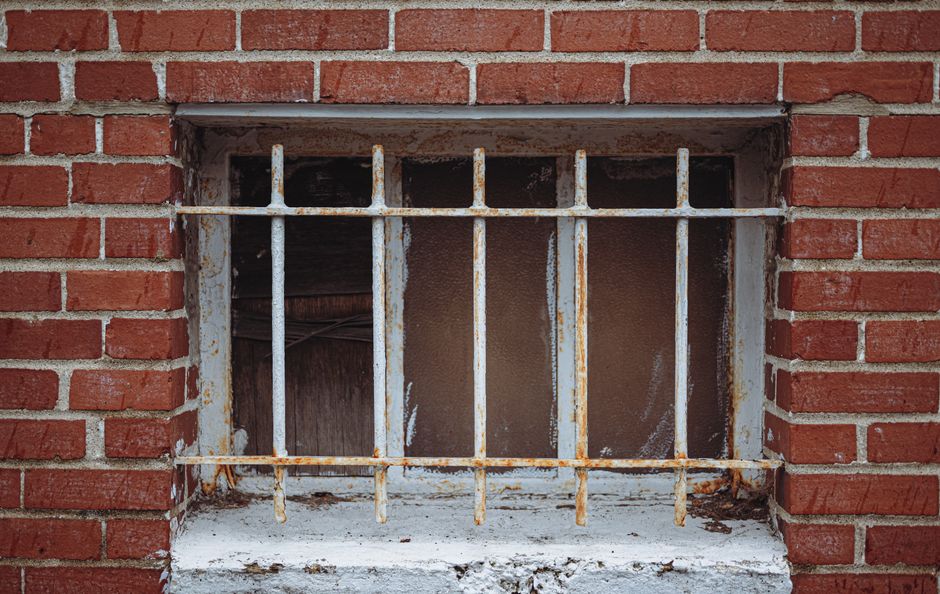 A corroded metal window well pulling away from a home's foundation wall